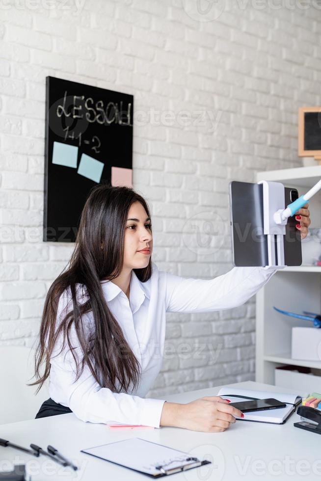 jovem latina de camisa branca ensinando inglês online foto