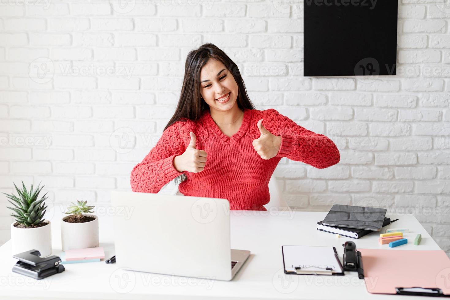 mulher com fones de ouvido pretos ensinando inglês online mostrando os polegares para cima foto