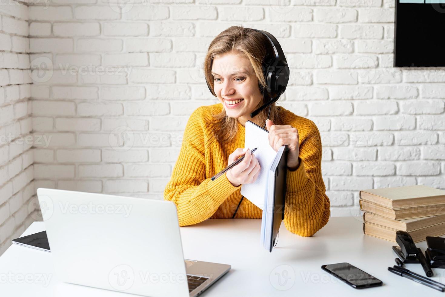 jovem com fones de ouvido pretos estudando on-line usando um laptop foto