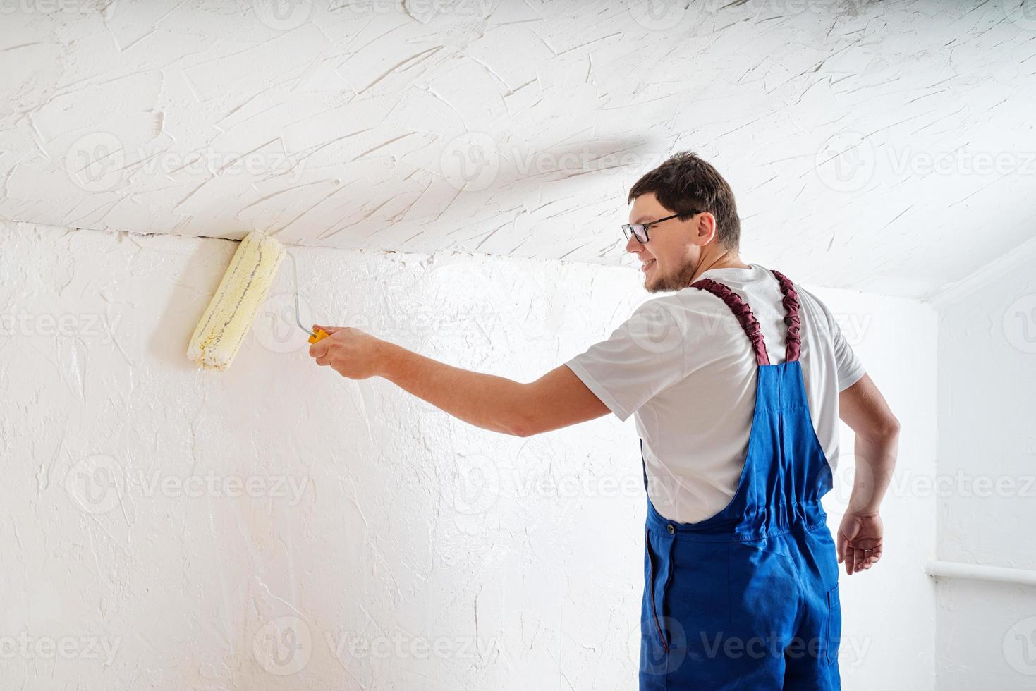 jovem de macacão azul pintando parede foto