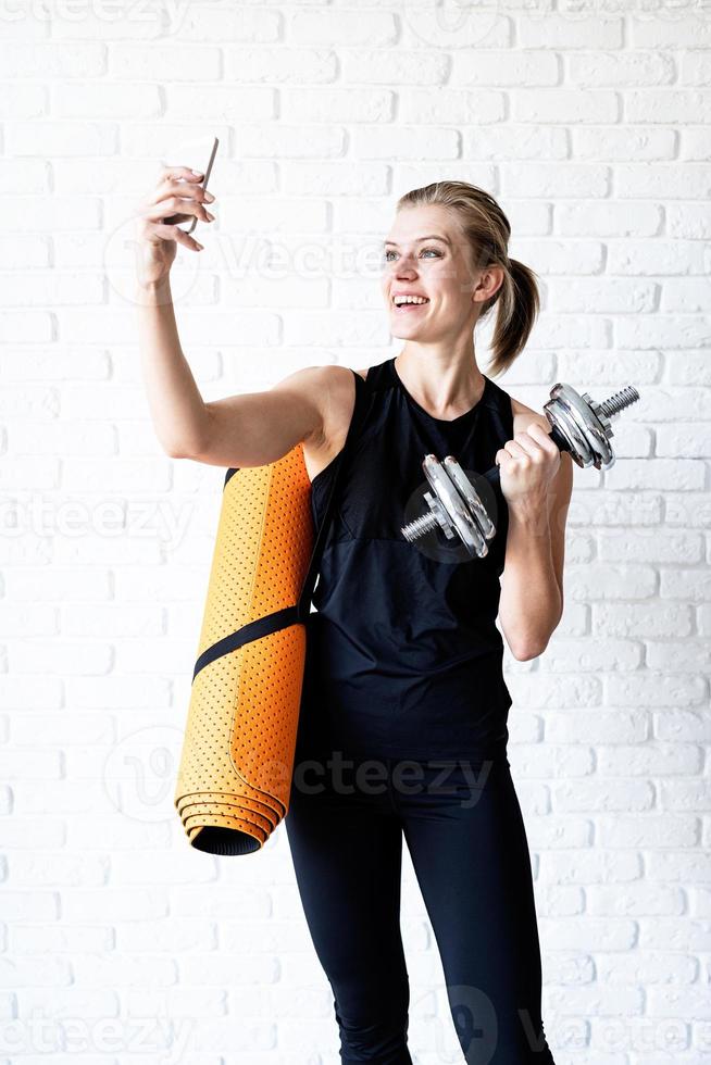 jovem sorridente fitness fazendo selfie após o treino foto