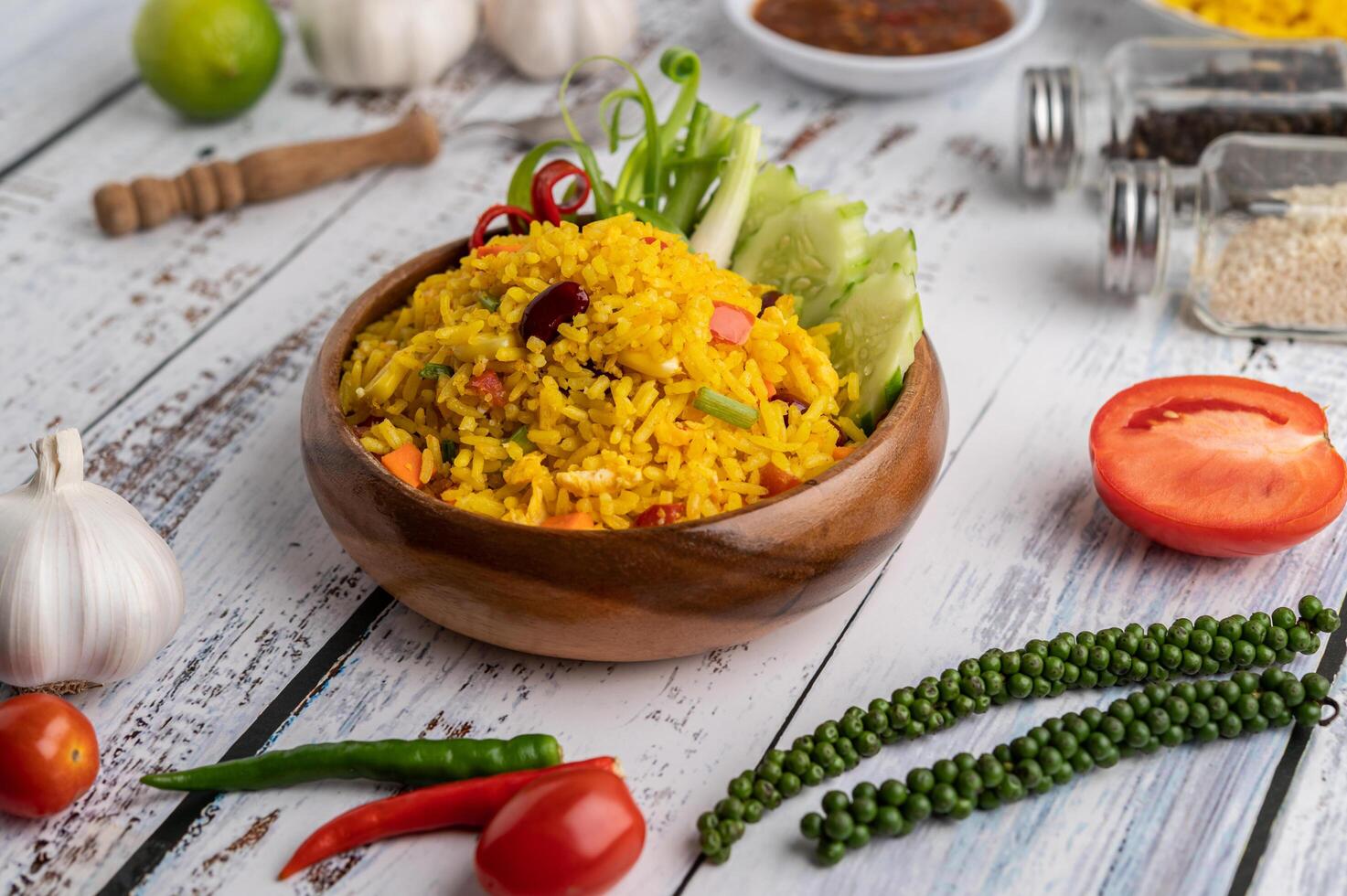 arroz de açafrão em um prato branco com especiarias em um piso de madeira branco foto