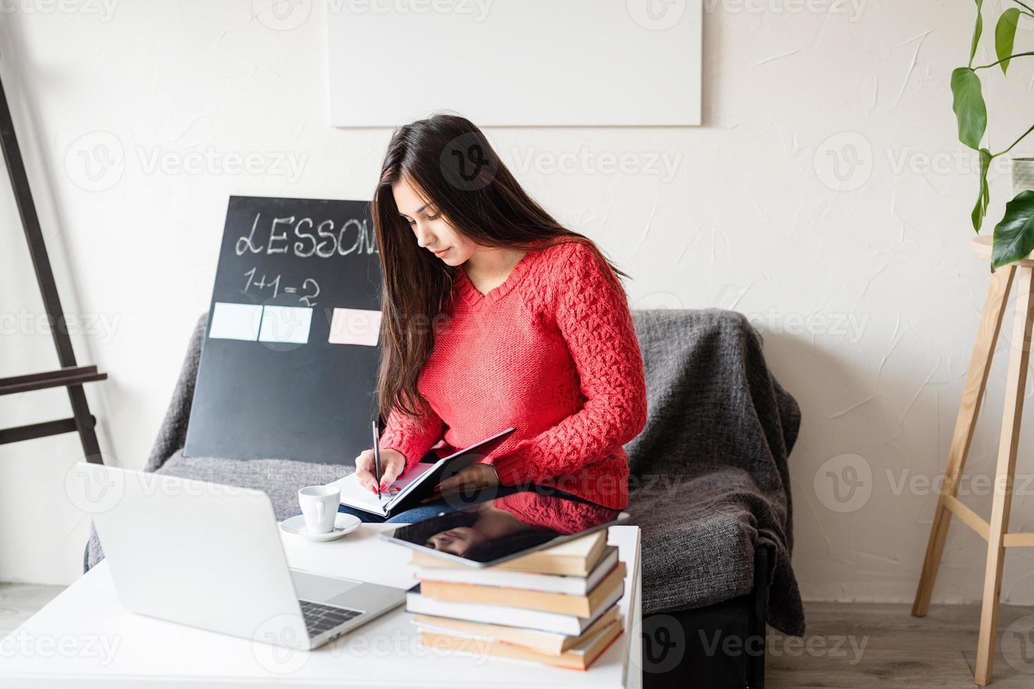 Uma mulher ensinando inglês online usando um laptop sentada no sofá foto