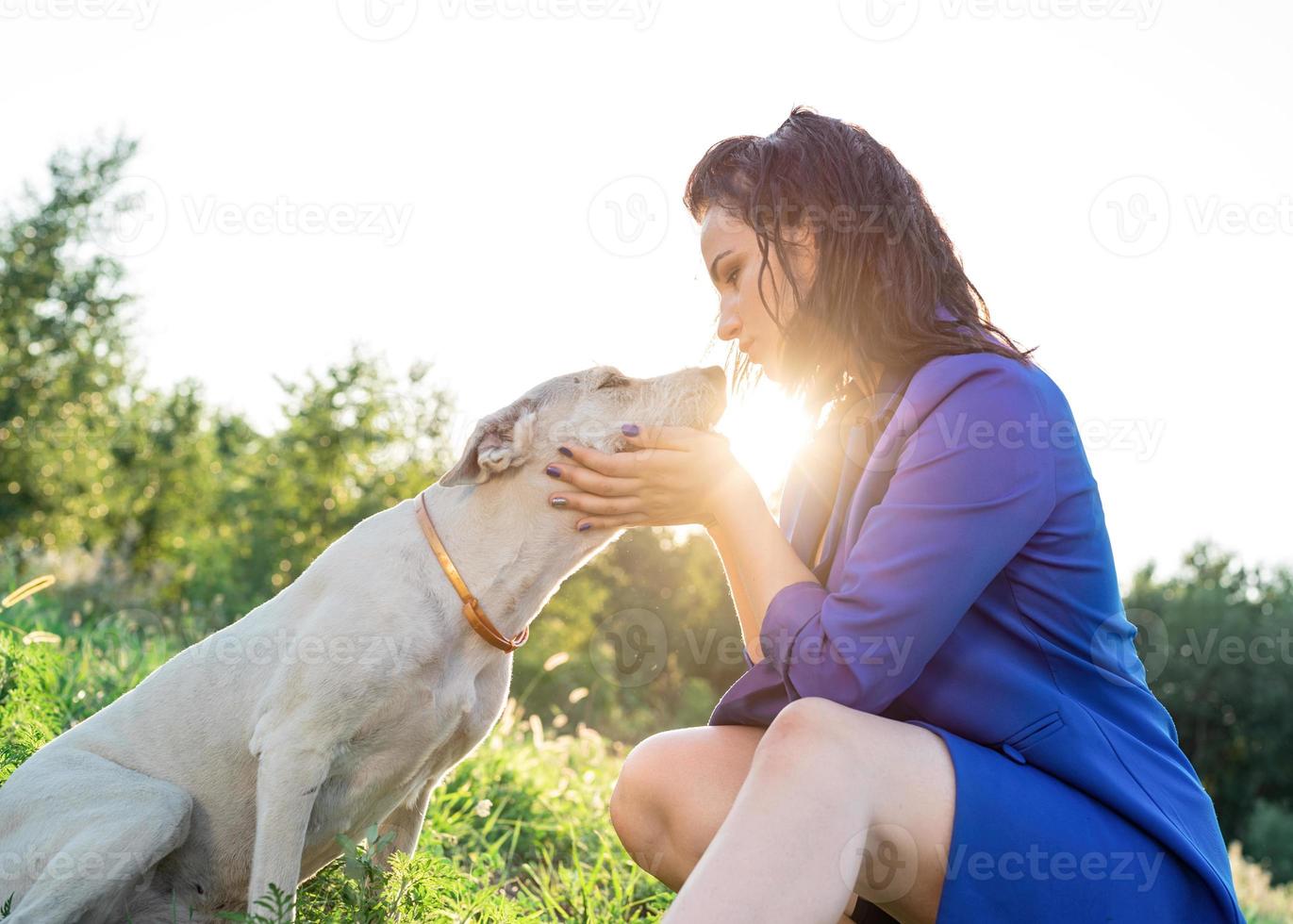 jovem mulher atraente abraçando seu cachorro no parque ao pôr do sol foto