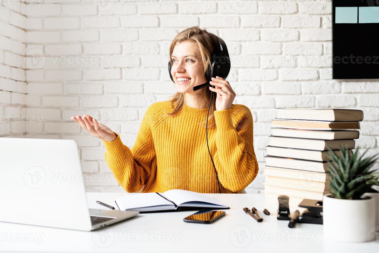 jovem sorridente com fones de ouvido pretos estudando on-line usando um laptop foto