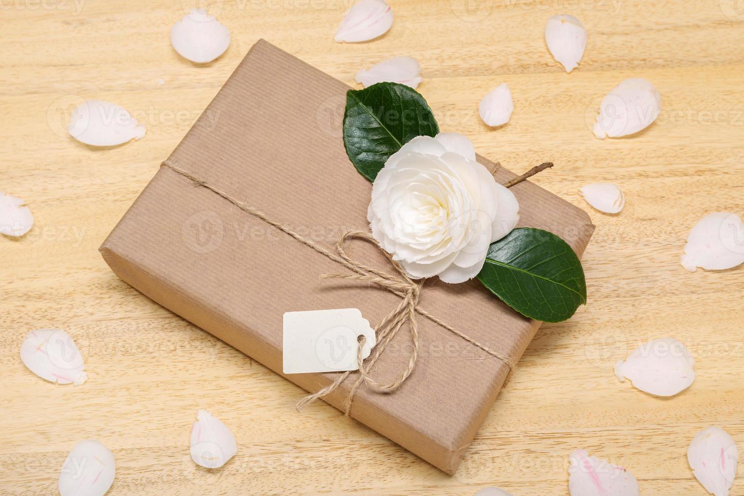 caixa de presente com etiqueta em branco e flor de camélia branca na mesa foto