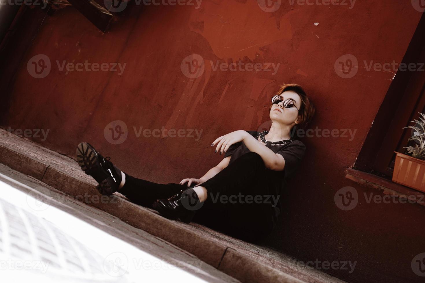 retrato de uma linda mulher sentada no chão sobre uma parede vermelha foto