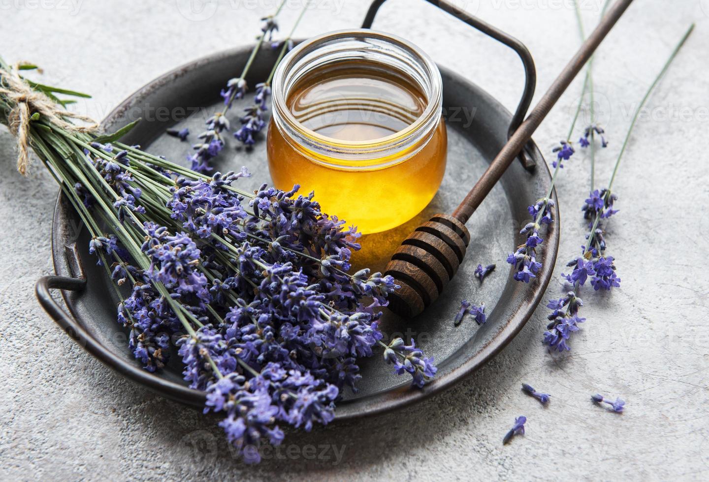 jarra com mel e flores frescas de lavanda foto