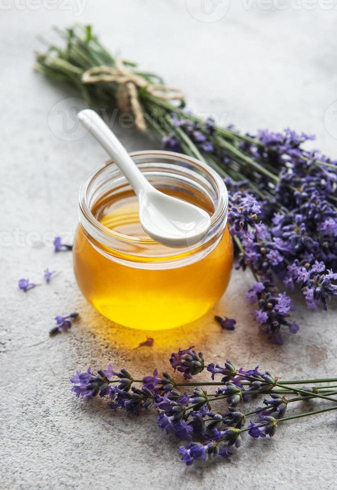 jarra com mel e flores frescas de lavanda foto