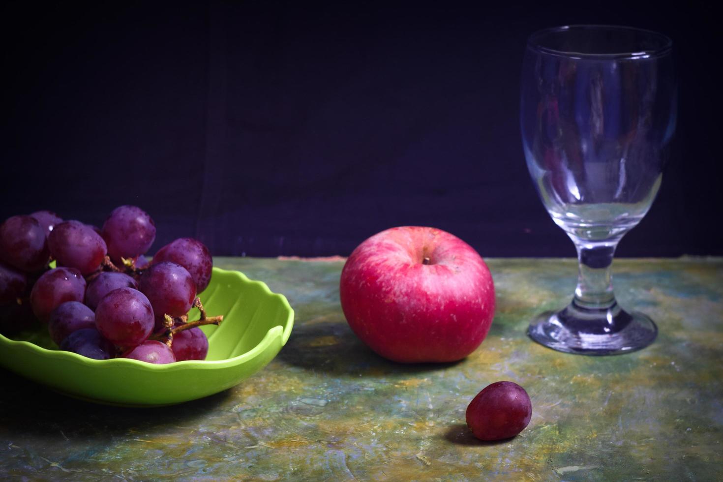 foto de natureza morta de maçãs e uvas em um fundo escuro