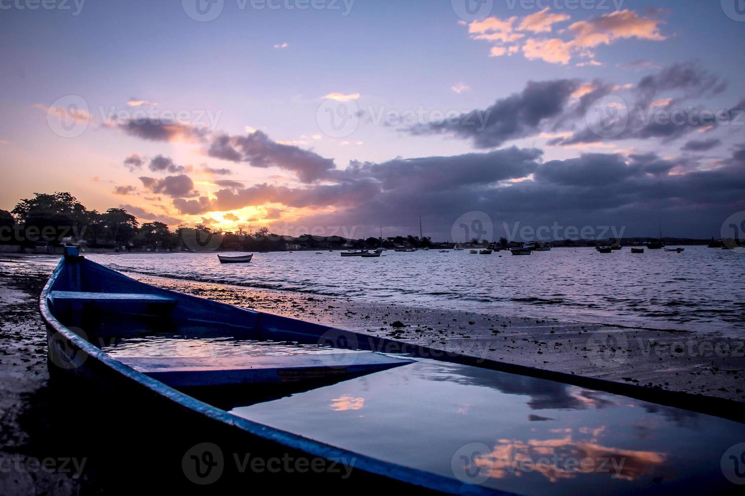 barco azul no pôr do sol, reflexo das nuvens na água foto