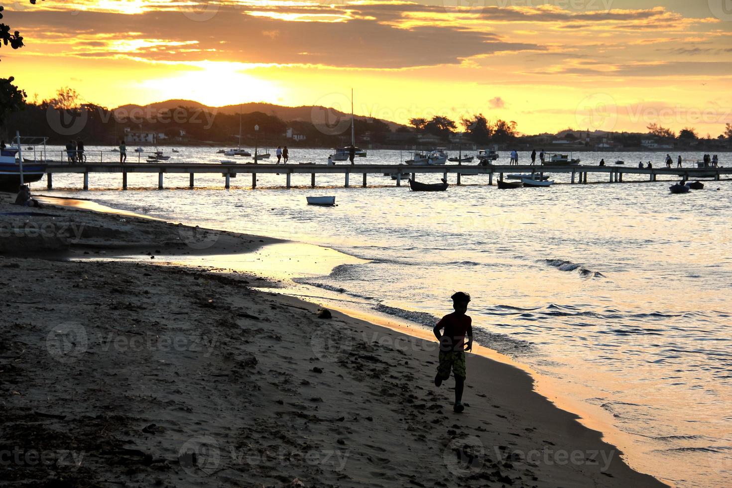 pôr do sol no cais, criança correndo em direção à câmera, imagem retroiluminada foto