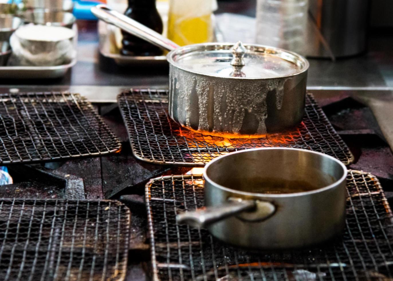 chef cozinhando com fogo em uma frigideira no fogão de cozinha foto