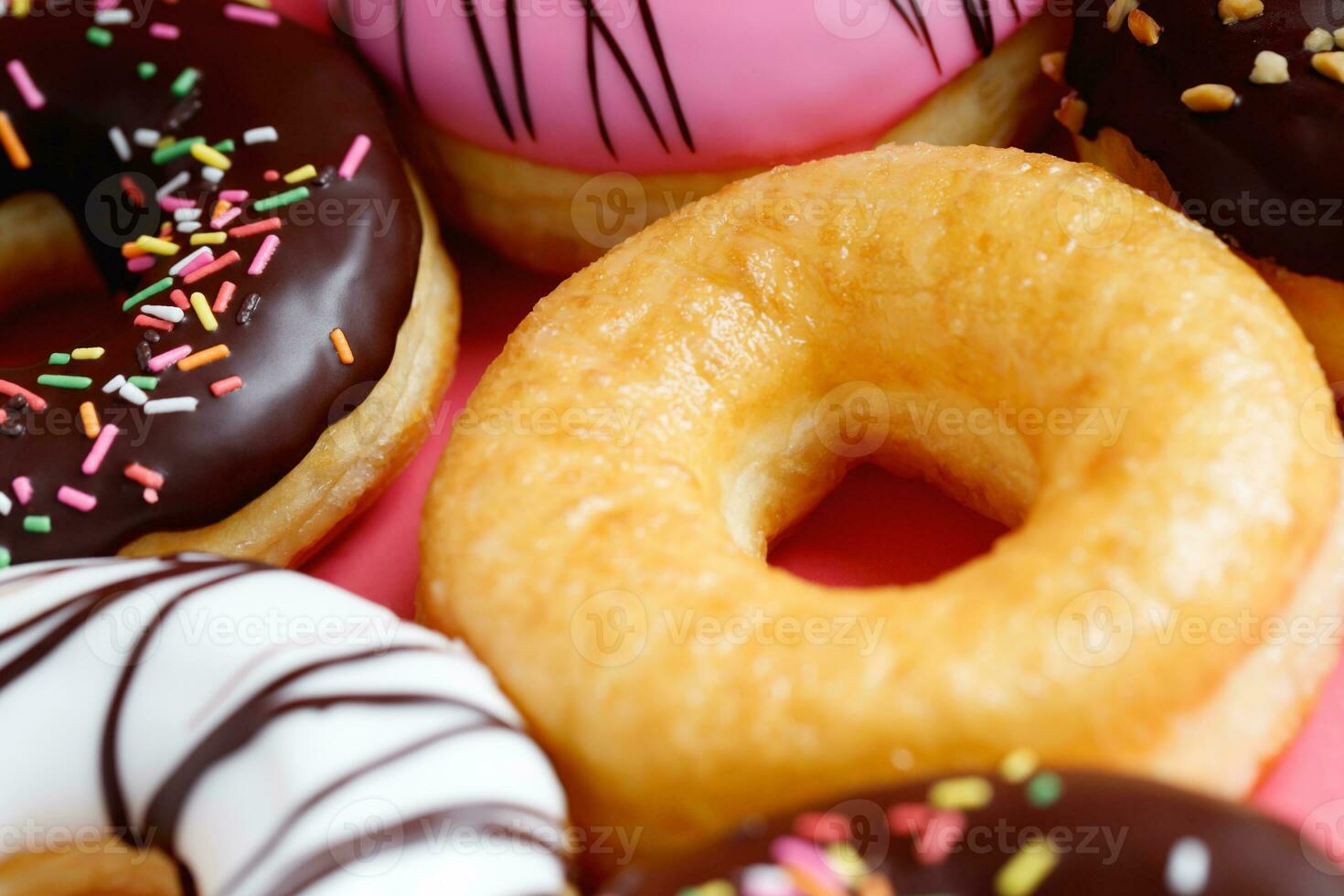 sortido rosquinhas com chocolate geada, cobertura granulados rosquinhas colorida variedade e variedade do sabores misturar do multi colori doce rosquinhas com fosco borrifado em Rosa fundo. topo Visão foto