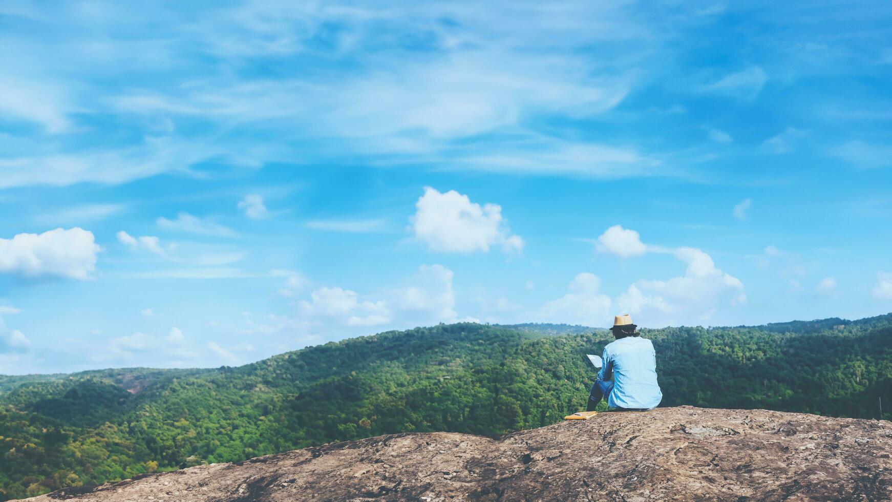 ásia homem viagem relaxar dentro a feriado. assentos relaxar ler livros em rochoso falésias. em a montanha verão. dentro Tailândia foto