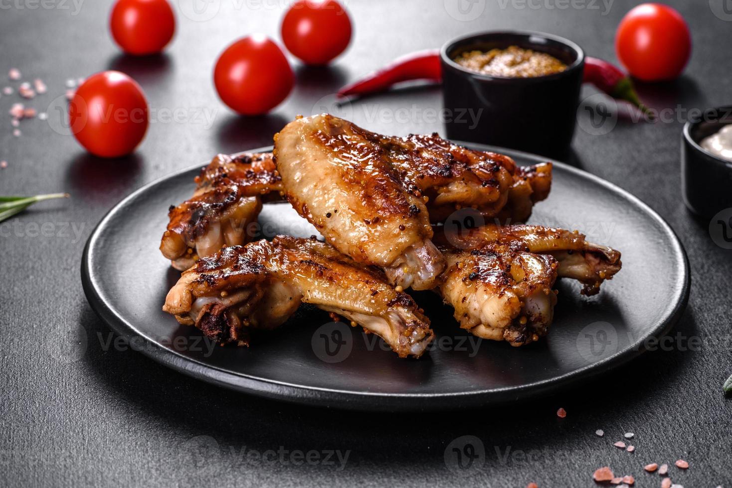 asas de frango picantes grelhadas em um fundo escuro com especiarias e ervas foto