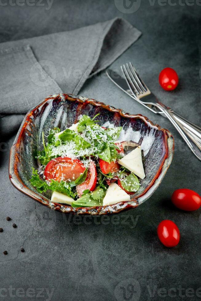 salada com tomates, feta queijo, alface e salsinha dentro a incomum tigela lado Visão foto
