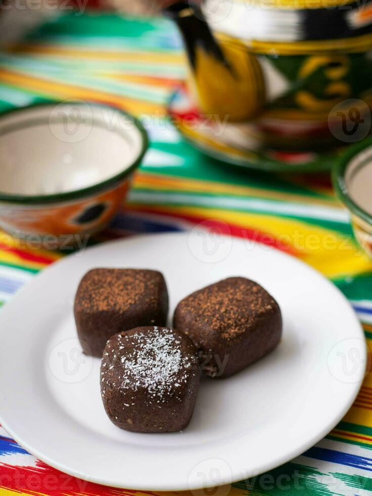 sobremesa chocolate Brownie batatas dentro oriental estilo em uma alcatrão com uma chaleira e uma copo para chá. foto