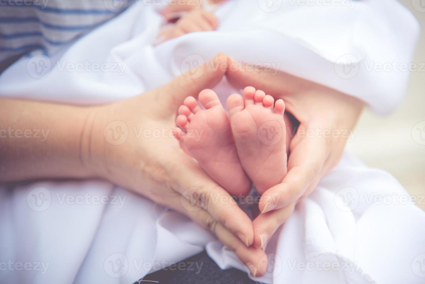 mãe segurando pés de bebê recém-nascido de pele macia e minúscula com as duas mãos foto