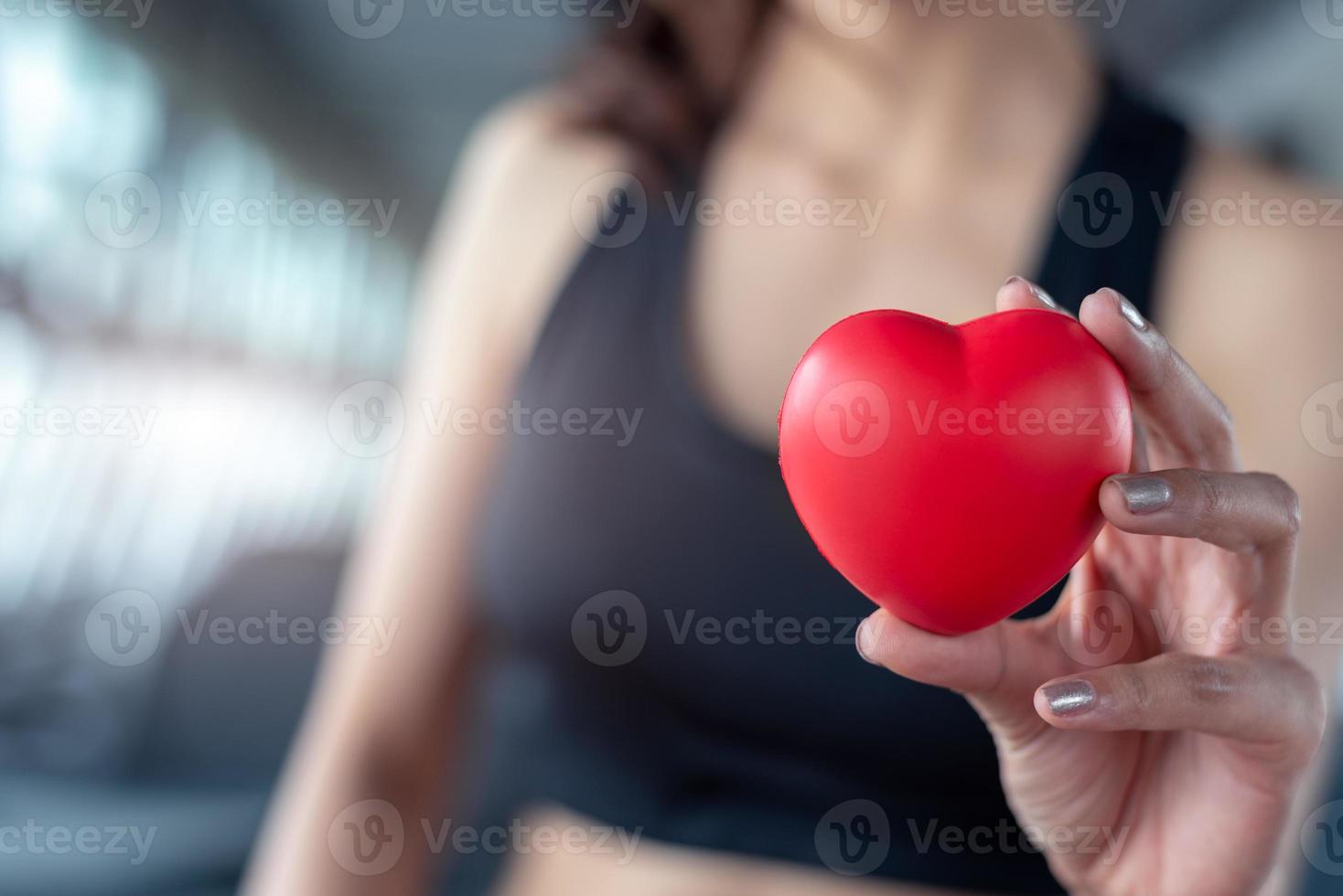 close-up da bola de massagem vermelha em forma de coração na mão de mulher fitness foto