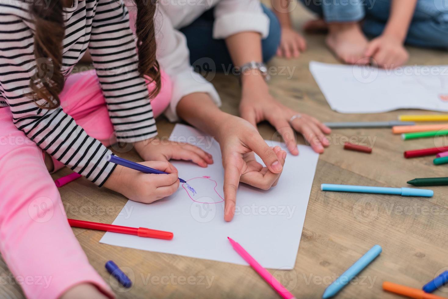 fechou as mãos da mãe ensinando crianças a desenhar desenhos animados foto