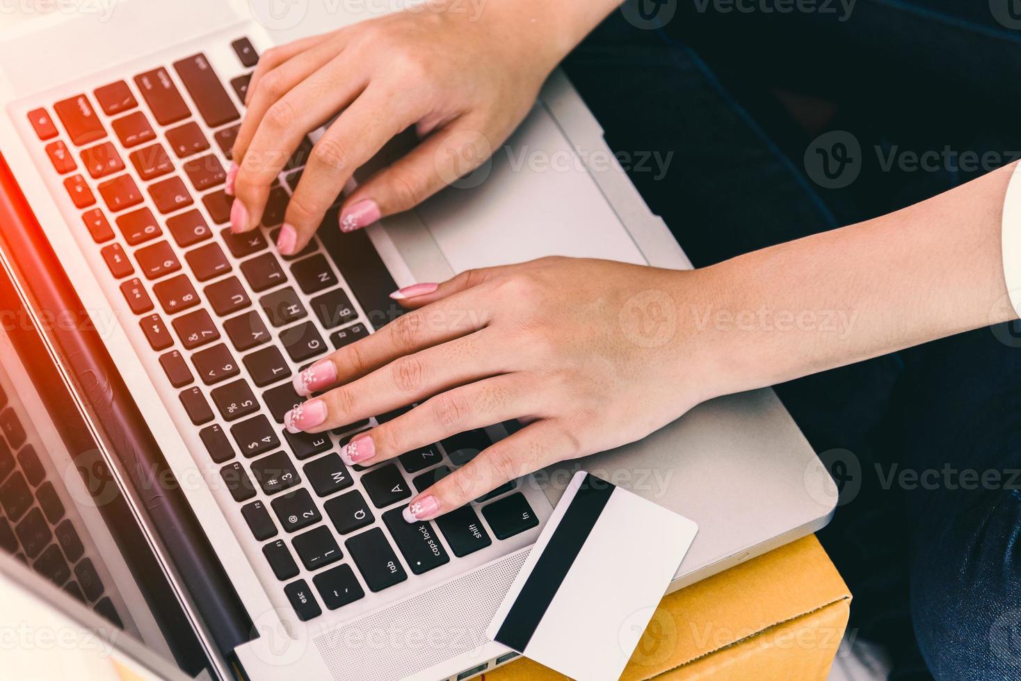 close-up de mãos de mulher usando laptop com cartão de crédito foto