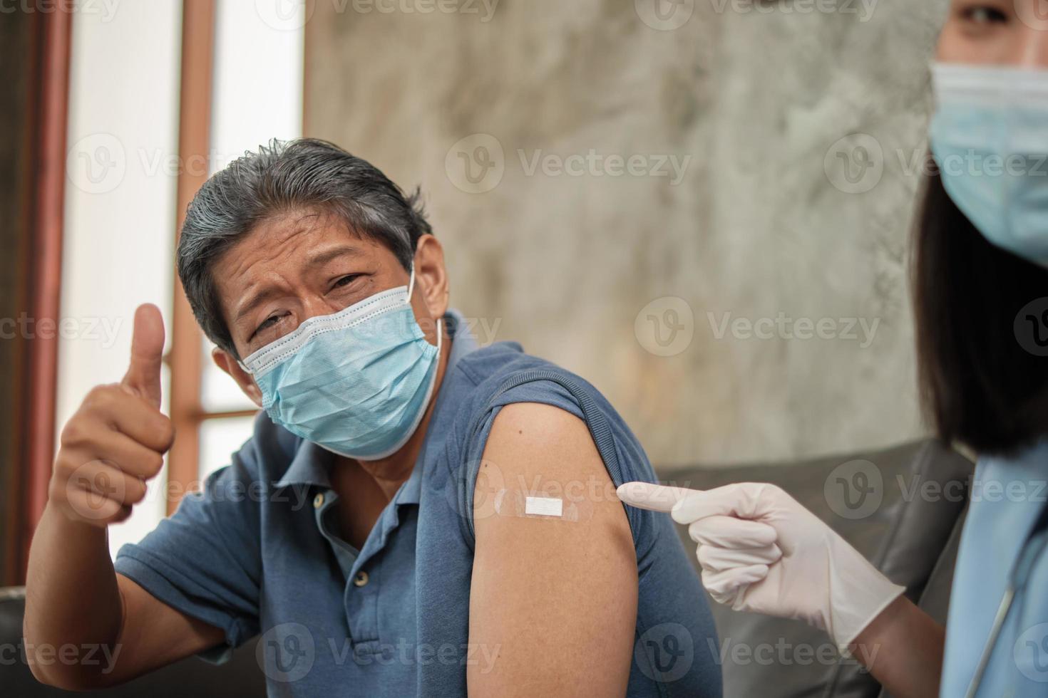 paciente idoso com máscara facial polegar para cima quando vacinado. foto