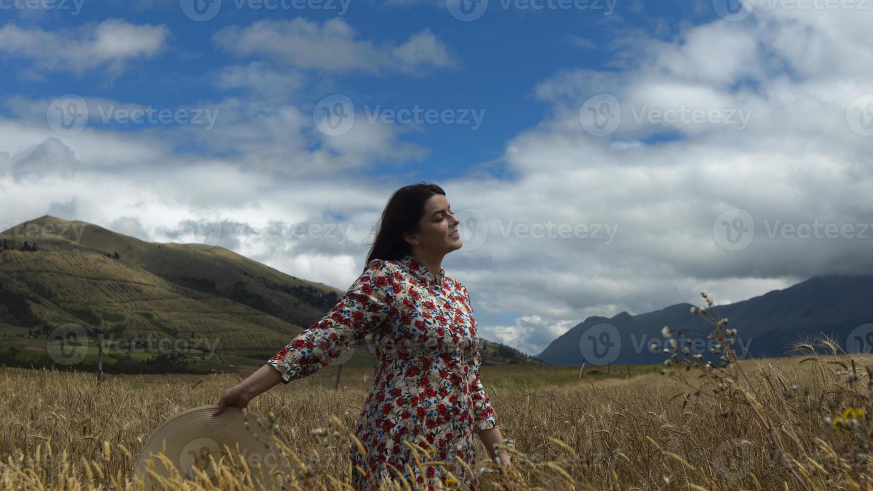 mulher com vestido floral caminhando no meio de um campo de trigo foto