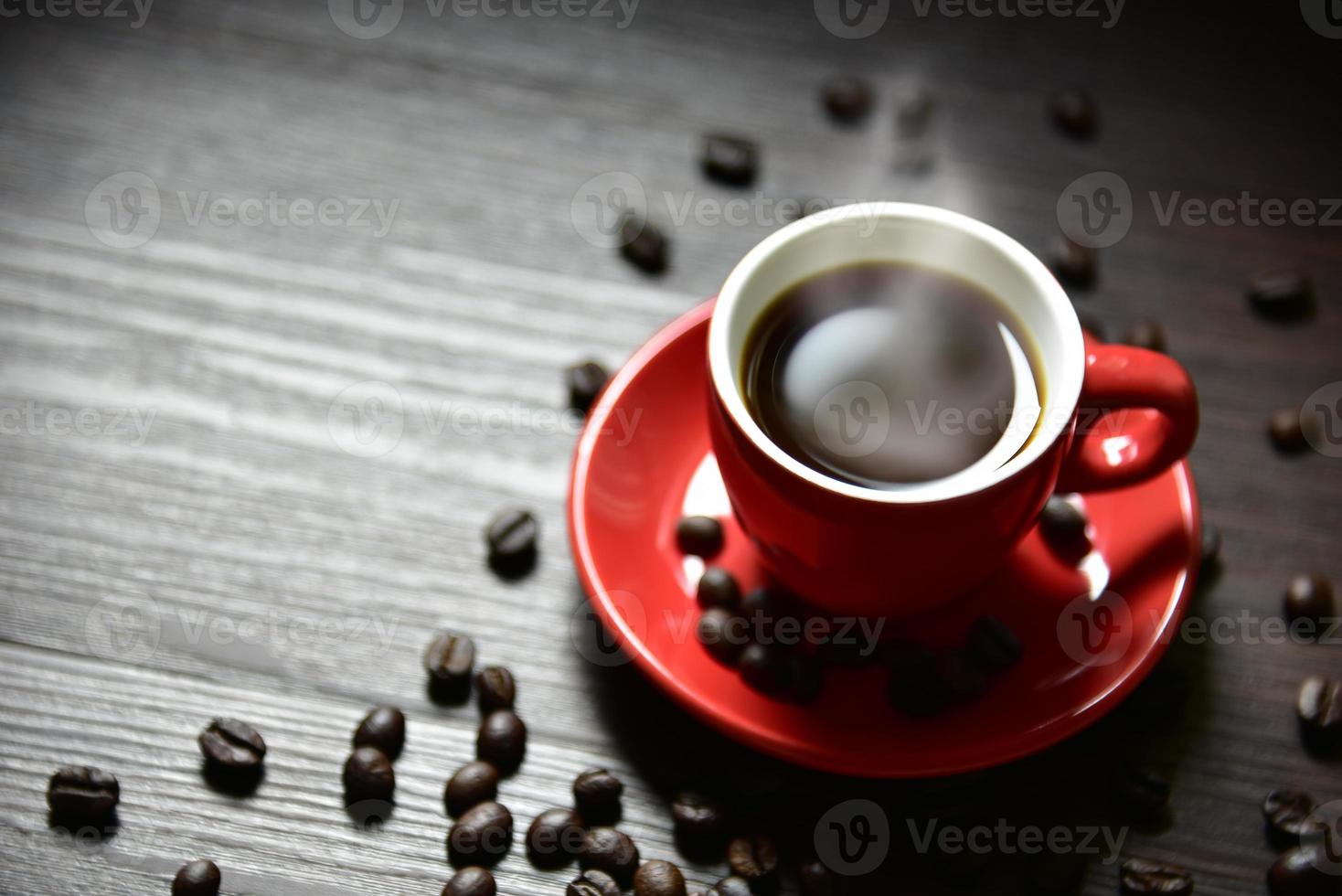 xícara de café vermelha com vapor e grão de café foto