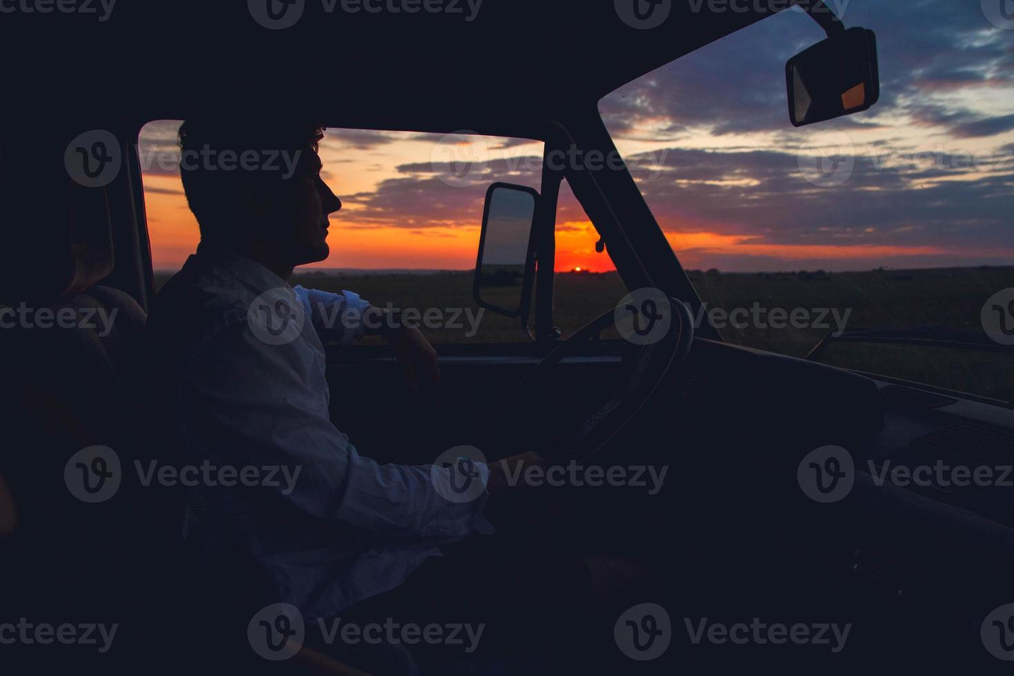 silhueta de homem dirigindo um carro no fundo do sol foto