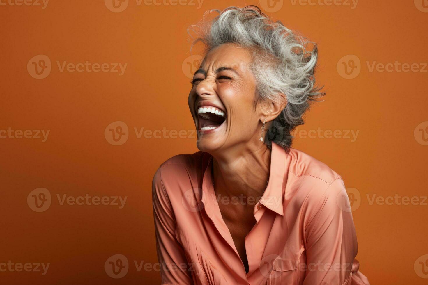 Senior mulher rindo cordialmente isolado em uma queimado Sienna gradiente fundo foto