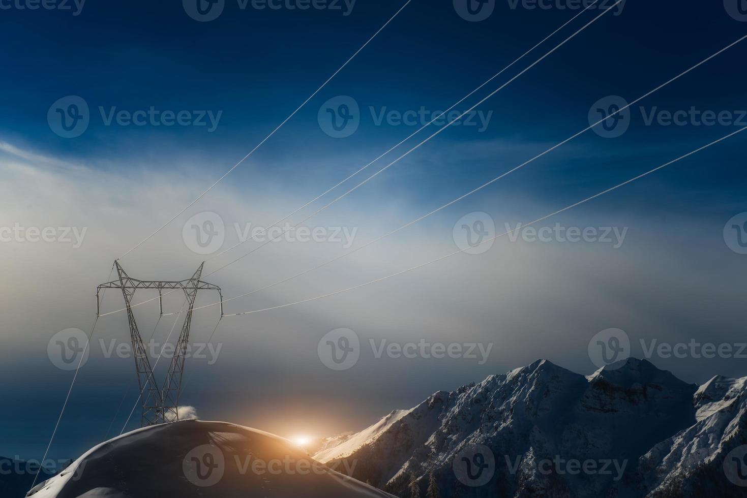 postes cobertos de neve nas altas montanhas carregam energia rio abaixo foto