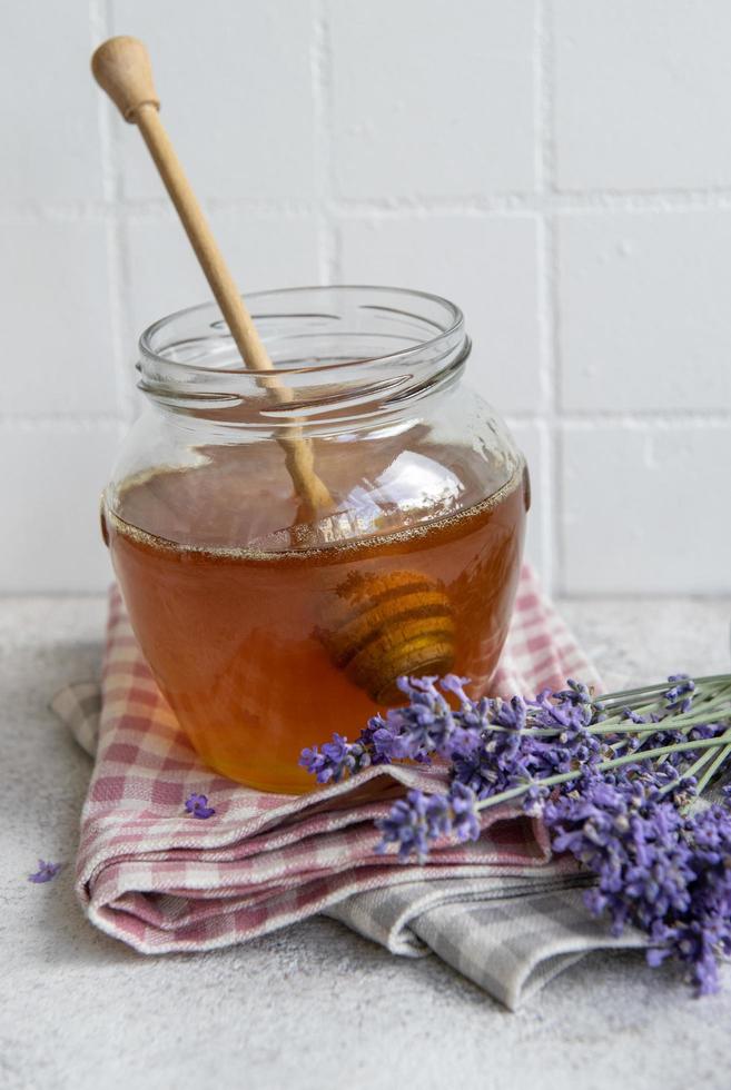 jarra com mel e flores frescas de lavanda foto