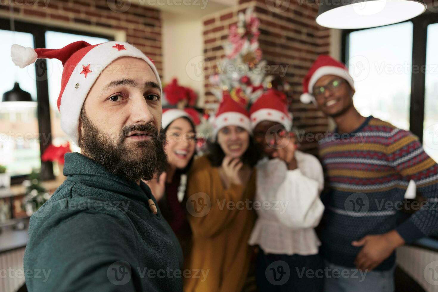 diverso trabalhadores levando Smartphone selfie às Natal corporativo festa dentro decorado escritório. colegas dentro santa chapéus posando para Móvel telefone foto enquanto a comemorar Novo ano às local de trabalho