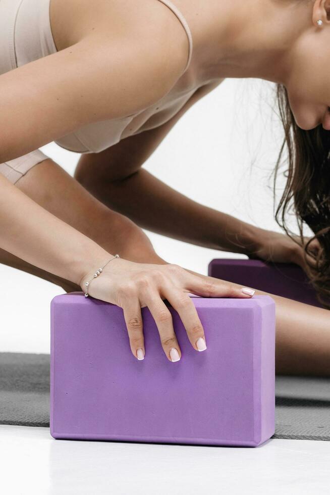 fechar-se mulher fazendo alongamento exercícios em uma branco fundo. espuma quadra ginástica equipamento foto