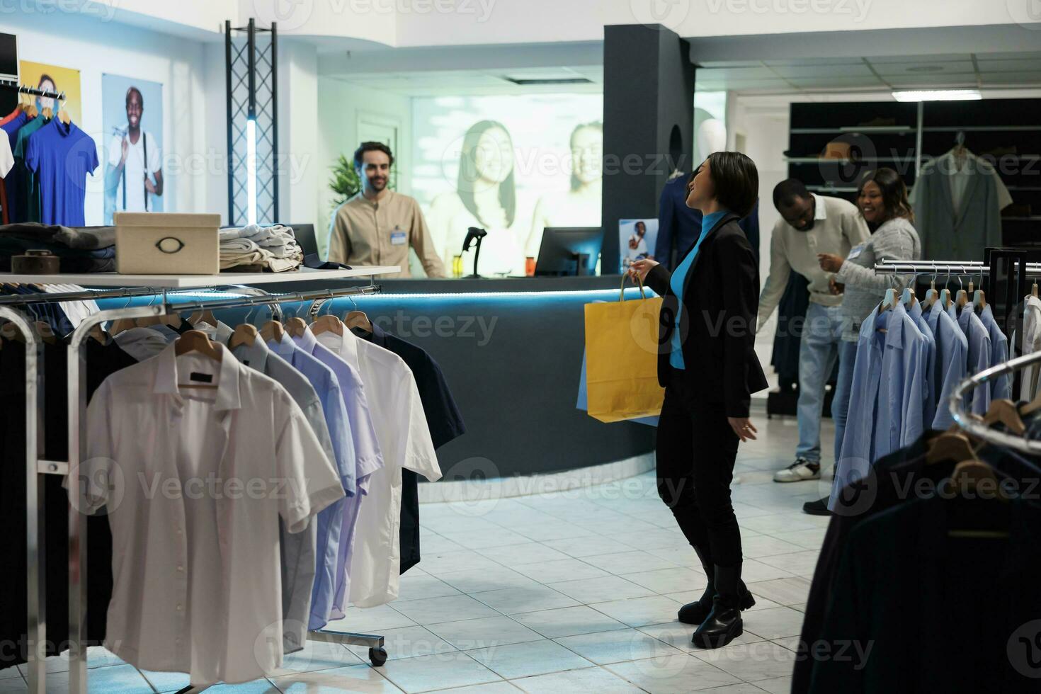 satisfeito cliente segurando compras bolsas e sorridente para caixa às roupas loja Verificação de saída escrivaninha. alegre sorridente ásia mulher carregando papel pacotes, em pé dentro boutique foto