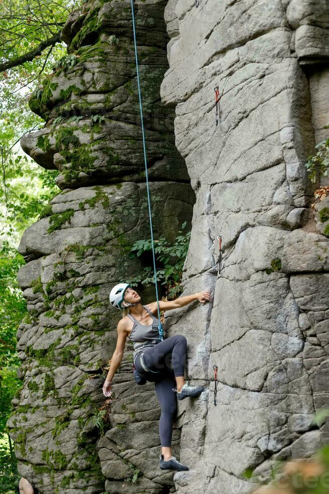 uma menina sobe uma Rocha. mulher acionado dentro extremo esporte. foto