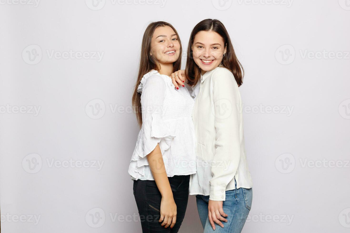 dois rindo meninas dentro branco em branco Camisetas olhando para dentro a Câmera foto