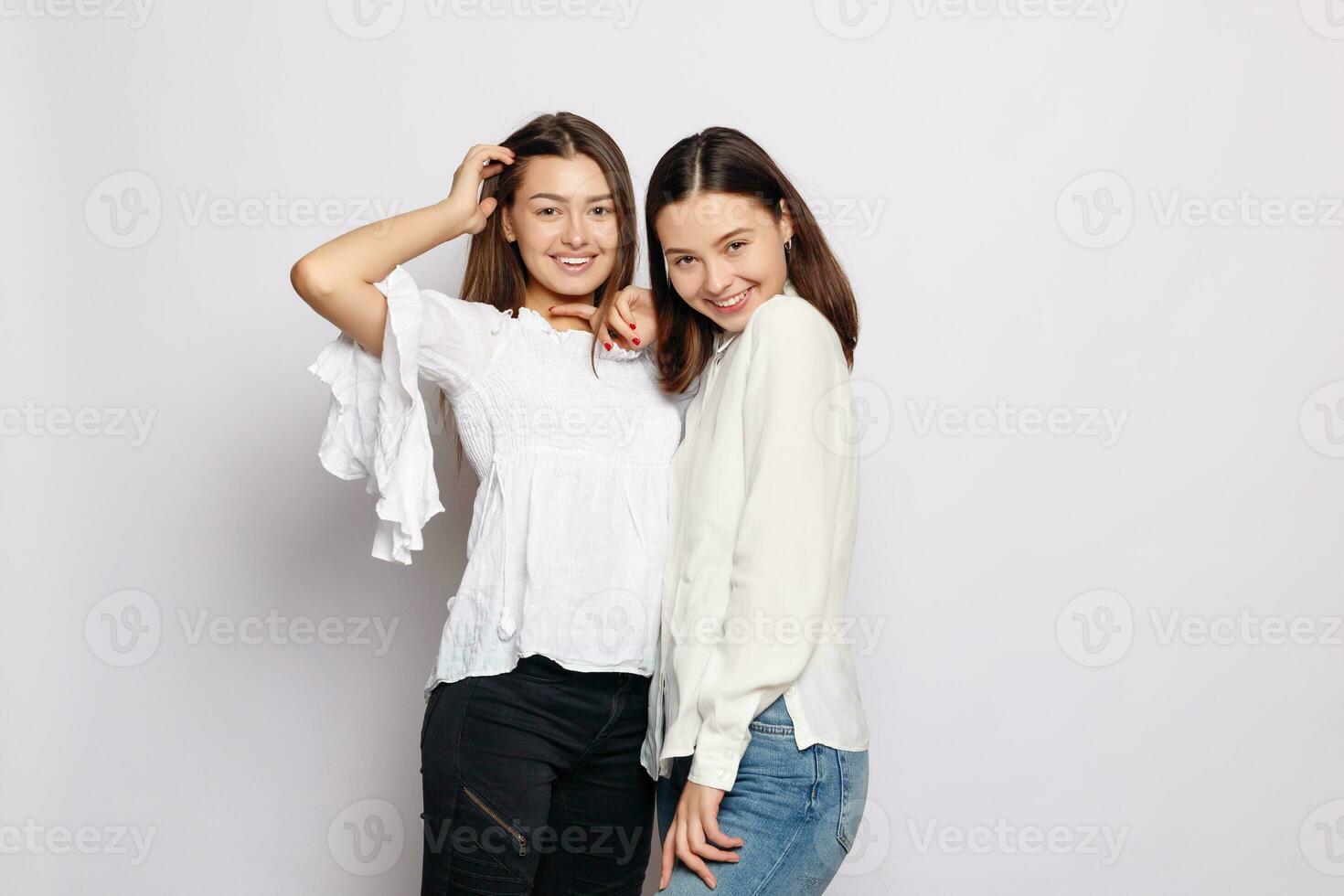 dois rindo meninas dentro branco em branco Camisetas olhando para dentro a Câmera foto
