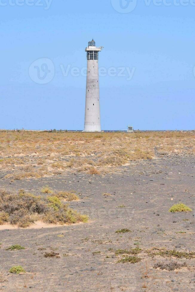 uma farol em uma estéril campo com uma azul céu foto