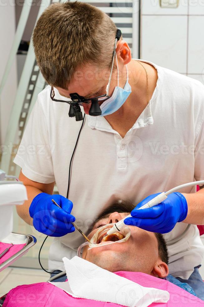 dentista na clínica, procedimento de remoção de tártaro. foto
