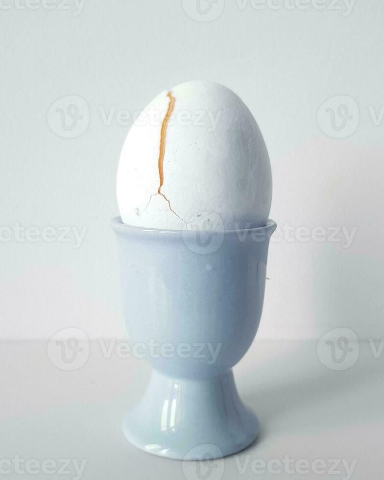 fervido ovo dentro uma azul eggcup em uma branco fundo. foto