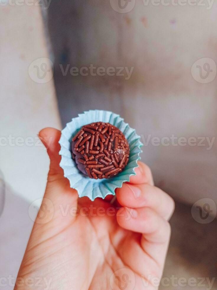 mão segurando chocolate trufas dentro uma azul papel Bolinho suporte foto