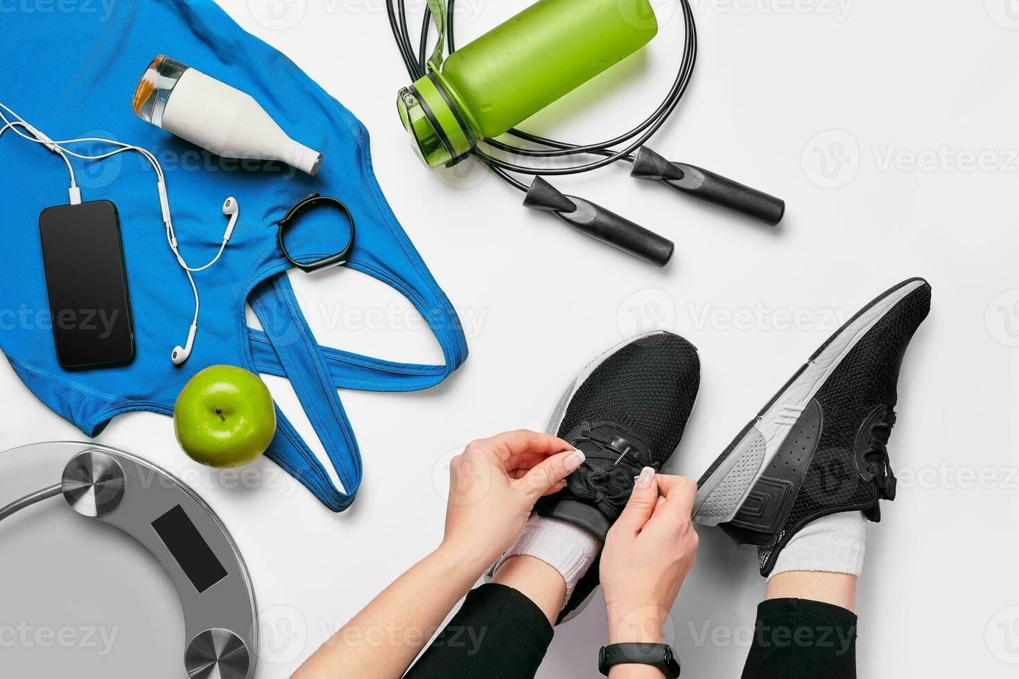 a sobrecarga Visão do mulher mãos amarrar sapatos com esporte equipamentos em branco fundo foto