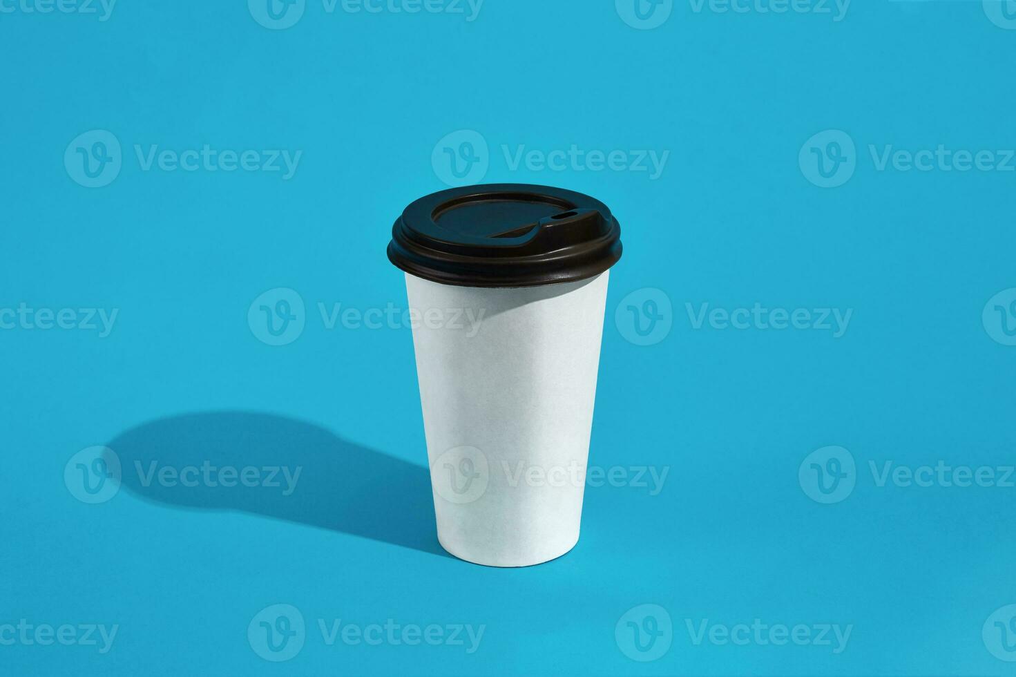 quente café dentro branco papel copo com Preto tampa em azul fundo foto