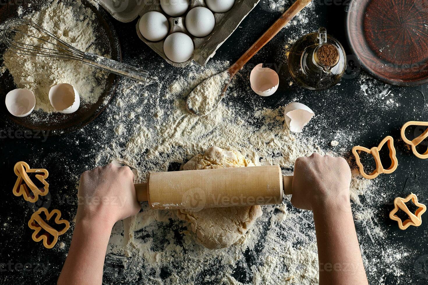 fêmea mãos rolando massa com uma rolando PIN em uma Preto mesa. topo Visão foto