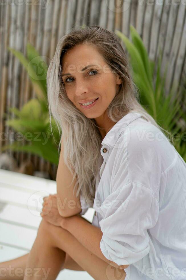 feliz loiro mulher dentro branco blusa posando dentro tropical recorrer. viajando e período de férias conceito. foto