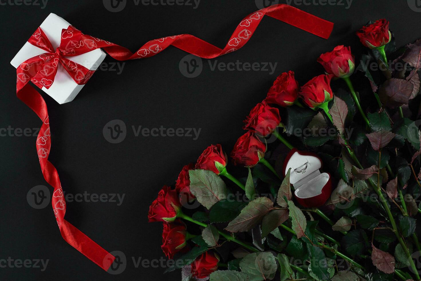 vermelho rosas, anel e presente caixa em Preto fundo foto