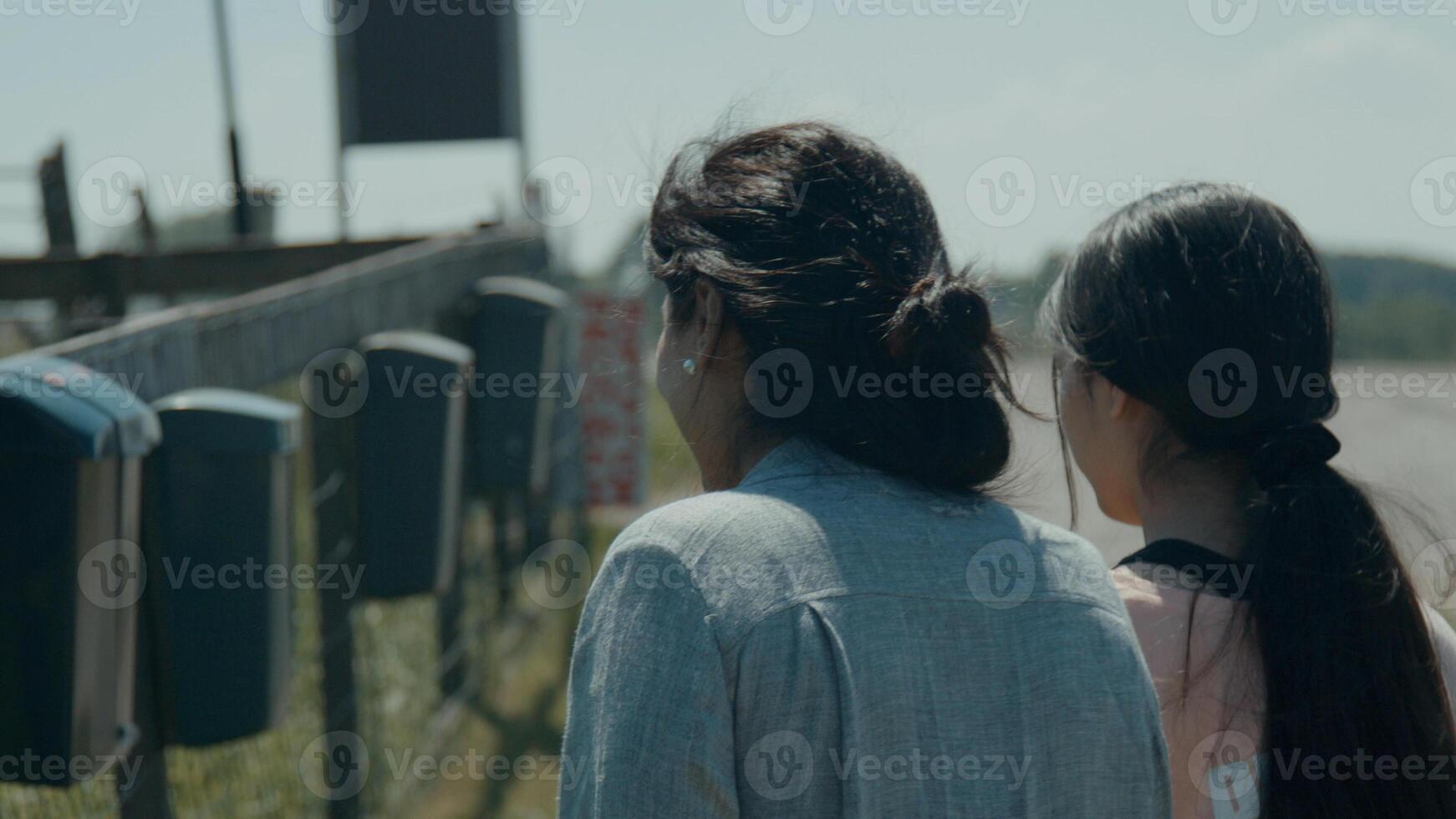 mulher e menina caminhando pelo campo vendo caixas de correio na cerca foto