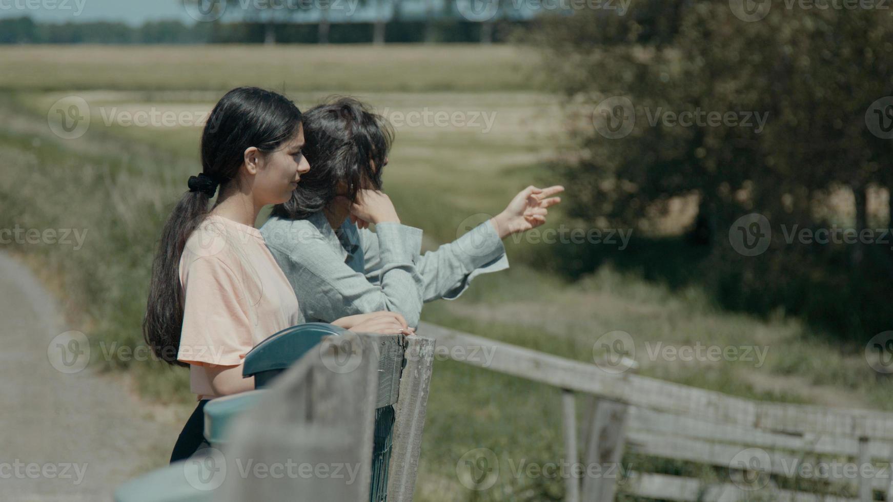 mulher e menina encostados na cerca no campo conversando foto